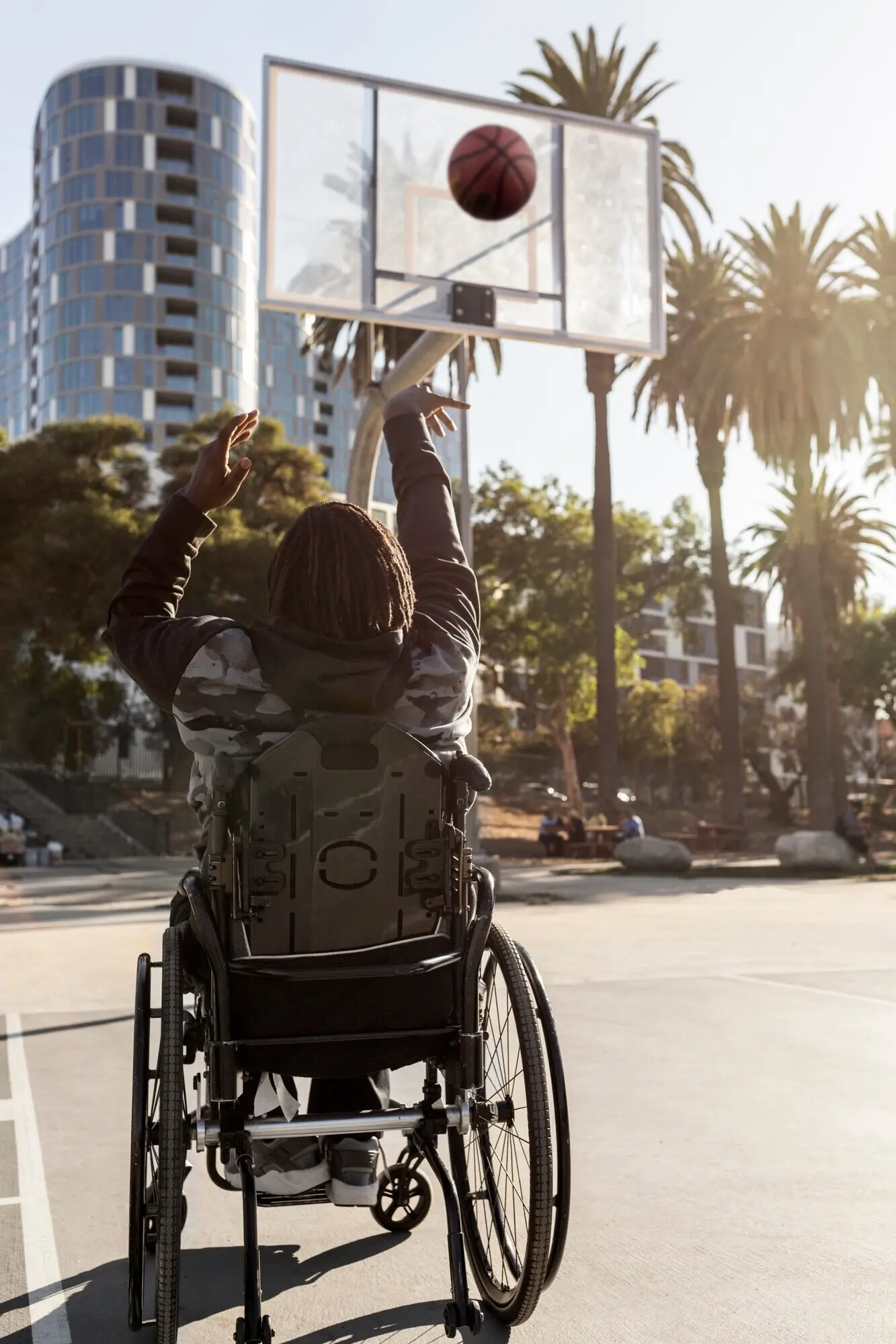 A disabled man in a wheelchair is playing basketball.