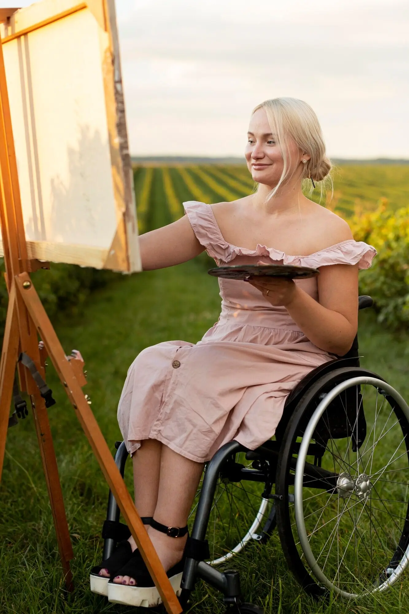 Smiling woman in a wheelchair painting outdoors